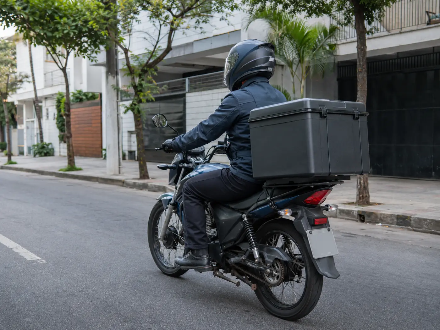Motoboy com capacete e motocicleta equipada com caixa de entrega